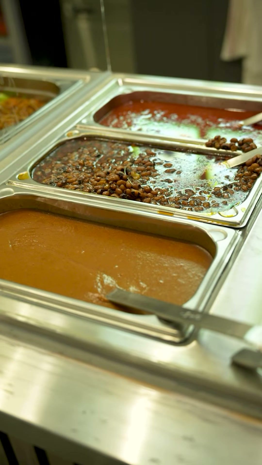 Warmhaltebehälter am Buffet mit Bohnen und verschiedenen Soßen